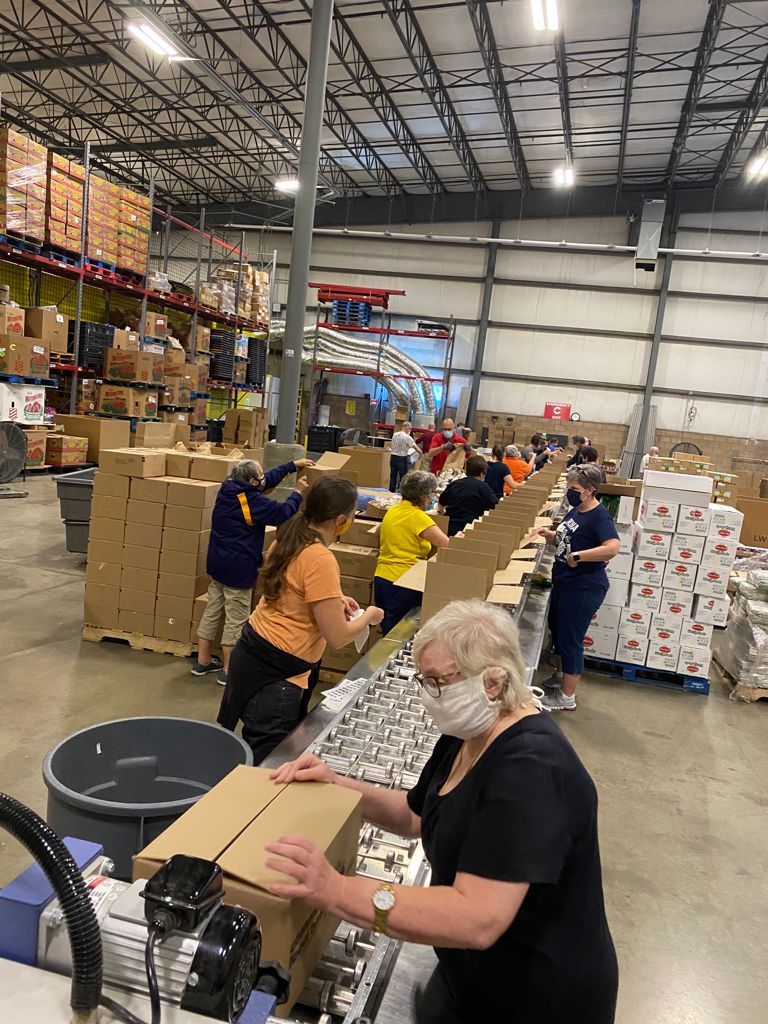 People in a warehouse loading boxes on an assembly line