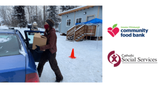 Volunteer loads food box into a car during a drive by distribution