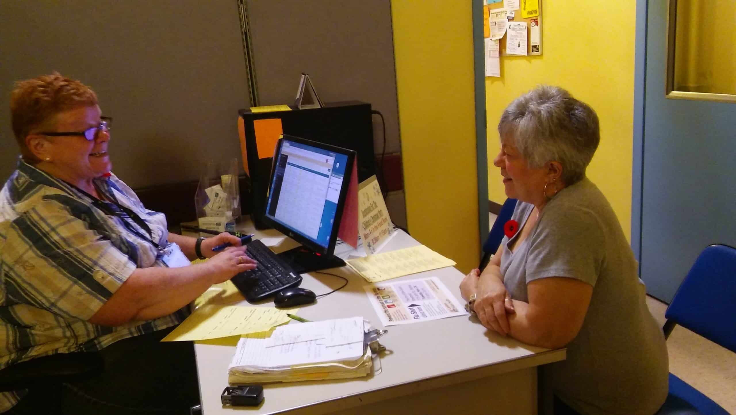 Woman checking in client using Link2Feed Case Management Software on a desktop