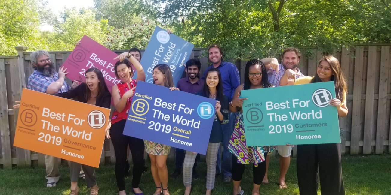 Link2Feed team posing with BCorp Best for the World Signs