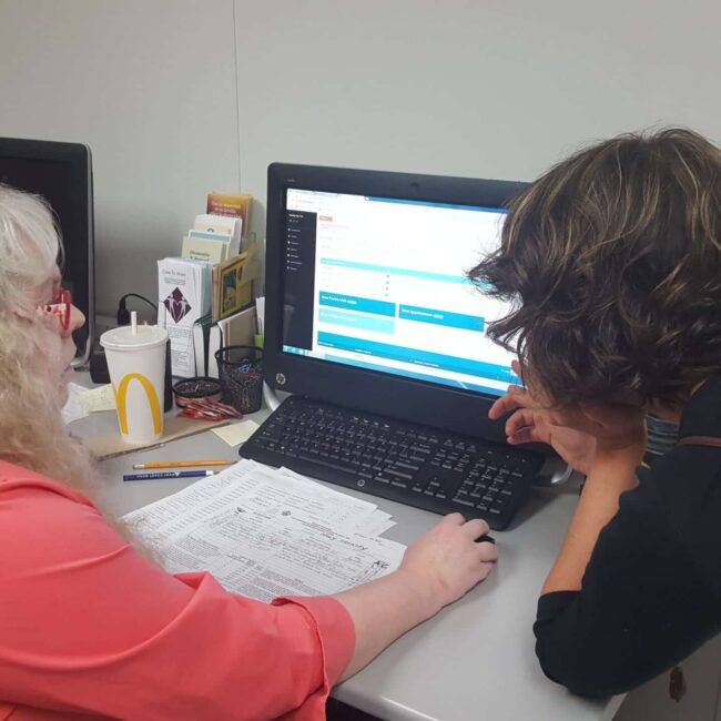 Woman showing man how to use Link2Feed Case Management Software on a desktop