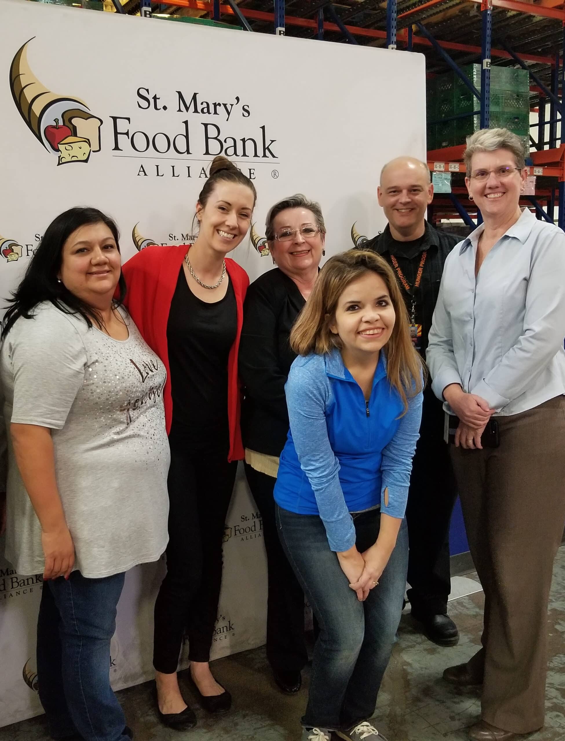 Link2Feed employee and food bank employees smiling in front of sign